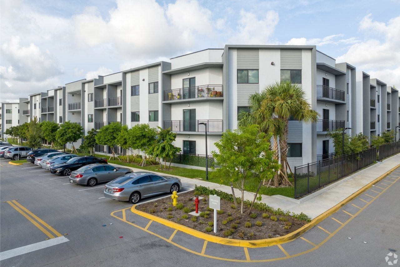 A parking lot with cars and apartment buildings in the background.
